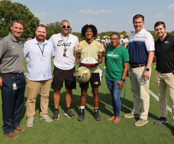  plano east football player josh palma with his football award standing with representatives